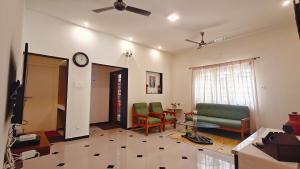 a living room with a couch and chairs and a clock at Sivam Villa-Kovalam in Covelong