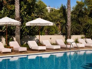 a pool with white lounge chairs and umbrellas at Abelia Boutique Rooms in Tsilivi