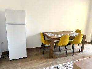 a dining room table with yellow chairs and a refrigerator at Villa Petra Residence - Private Parking & Village Life in Cristian