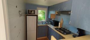 a kitchen with blue cabinets and a white refrigerator at vent de liberté 80 camping les peupliers in Vironchaux