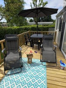 a deck with a table and chairs and an umbrella at vent de liberté 80 camping les peupliers in Vironchaux