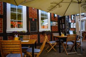 zwei Tische und Stühle mit Sonnenschirmen vor einem Restaurant in der Unterkunft Restaurant und Pension Zur Wildgans in Arendsee