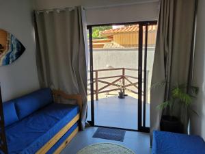 a living room with a blue couch and a balcony at Pontal Flat 103 in Coruripe +23 photos