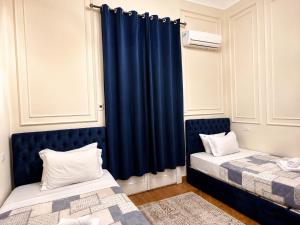 two beds in a room with blue curtains at Yacoubian Suites in Cairo +9 photos