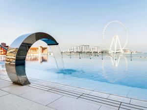 a fountain in a pool with a ferris wheel in the background at Sofitel Dubai Jumeirah Beach in Dubai