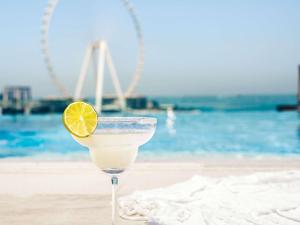 a drink with a lemon slice in a glass on the beach at Sofitel Dubai Jumeirah Beach in Dubai