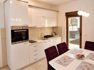 a kitchen with white cabinets and a table with chairs at Apartmani Sofrenic-Adonis in Zlatibor