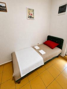 a small bed in a room with a red pillow at Dodo Obala Apartmani in Sutomore