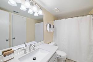 a bathroom with a sink and a toilet and a mirror at Beachfront Paradise at Phoenix II 2046 in Orange Beach +3 photos