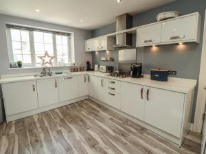 a kitchen with white cabinets and a wooden floor at Sugar Loft in Wigton