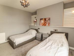 a bedroom with two beds and a chandelier at Sugar Loft in Wigton
