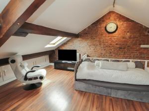 a bedroom with a brick wall with a bed and a clock at Sugar Loft in Wigton