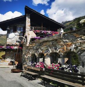 a stone building with flowers in front of it at Baita La Jolie Bergere in La Salle