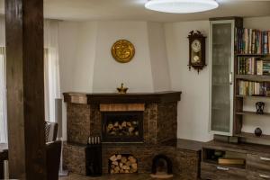 a living room with a stone fireplace with a clock at Green Valley Guesthouse in Izvoru Mureşului