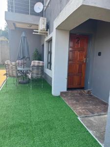 a patio with green grass in front of a house at The Well Apartments in Mbabane