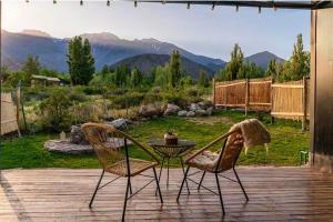 two chairs and a table on a deck with a view at El Castaño Apart in Potrerillos