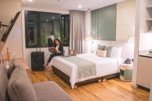 a woman sitting on a bed in a hotel room at Hotel Ryo 74B Suites by Growing Group in Medellín +108 photos