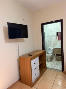 a bathroom with a toilet and a television on the wall at Pousada Flor do Vale in São José dos Campos