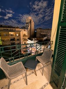 two chairs on a balcony with a view of a city at Yacoubian Suites in Cairo