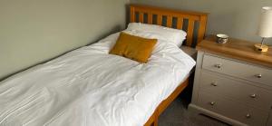 a bed with white sheets and a brown pillow on it at Shepherd's Lodge in Skipton