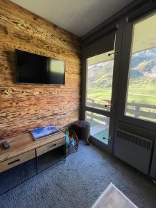 a living room with a flat screen tv on a wooden wall at Panorama à La Mongie in La Mongie