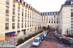 a parking lot with cars parked in front of buildings at Le Petit Attique de Versailles in Versailles +1 photo