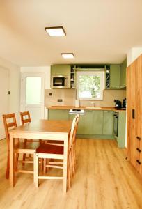 a kitchen with green cabinets and a wooden table and chairs at Officium P47 in Rakamaz +6 photos