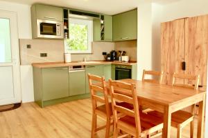 a kitchen with a wooden table and green cabinets at Officium P47 in Rakamaz