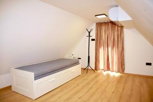 a white bedroom with a bed and a window at Officium P47 in Rakamaz