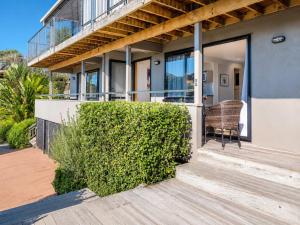 a house with a balcony with a chair on the porch at Aqua Sands #1 - Stay Waiheke in Oneroa +4 photos