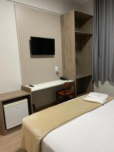 a hotel room with a bed and a flat screen tv at Serra Palace Hotel in Ouro Branco