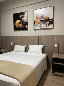 a bedroom with a large bed with two pictures on the wall at Serra Palace Hotel in Ouro Branco