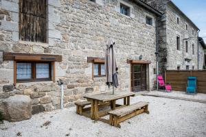 a picnic table and an umbrella in front of a building at la bergerie in Mialanes