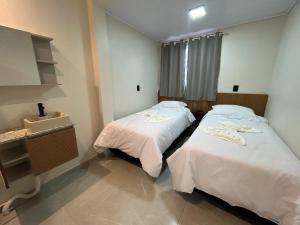 a room with two beds and a sink in it at Castilhos Hotel in Barracão