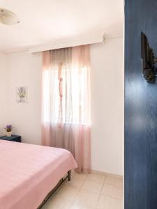 a bedroom with a pink bed and a window at Louis' apartment with view in Gythio