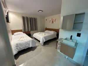 a hospital room with two beds and a sink at Castilhos Hotel in Barracão
