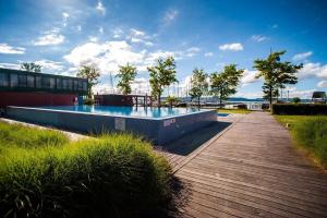 a swimming pool with a wooden walkway next to a building at Balino 57 in Balatonlelle