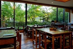un restaurante con mesas, sillas y ventanas grandes en Shibu Hotel, en Yamanouchi