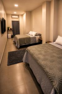 a bedroom with two beds and a television in it at Sely Suítes in Ametista do Sul