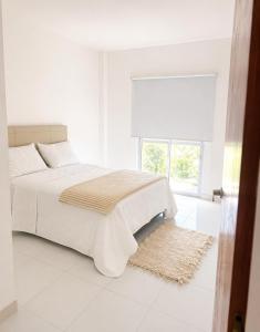 a white bedroom with a bed and a window at Departamento in Formosa