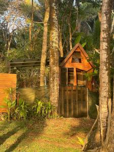 a small house behind a wooden fence with trees at Private Beachfront Beach Hut in Manzanillo