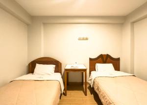 a small room with two beds and a table at Hotel Qoyllur urcos in Urcos