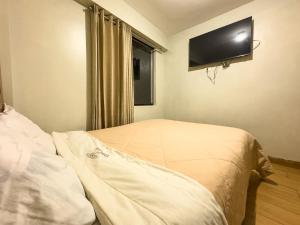 a bedroom with a bed with a television on the wall at Hotel Qoyllur urcos in Urcos +4 photos