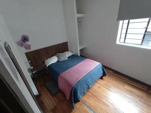 a small bedroom with a bed with a colorful blanket at Hostal Schultz in Mexico City