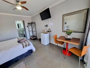 a bedroom with a bed and a desk and a table at Kaleaba House on the Riverside in Parys