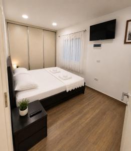a bedroom with a large bed and a flat screen tv at Apartament Drasa in Gjirokastër
