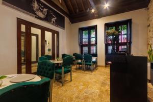 a restaurant with green chairs and tables and windows at Hotel Boutique Santo Toribio in Cartagena de Indias