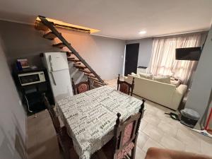 a living room with a table and a kitchen with a staircase at Deptos Valen in Trevelín