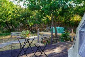 a table and chairs on a deck next to a tent at glamping giardino museo a gisa in Petralia Sottana