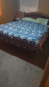 a bed with a blue comforter on top of it at Casa de campo in Colina